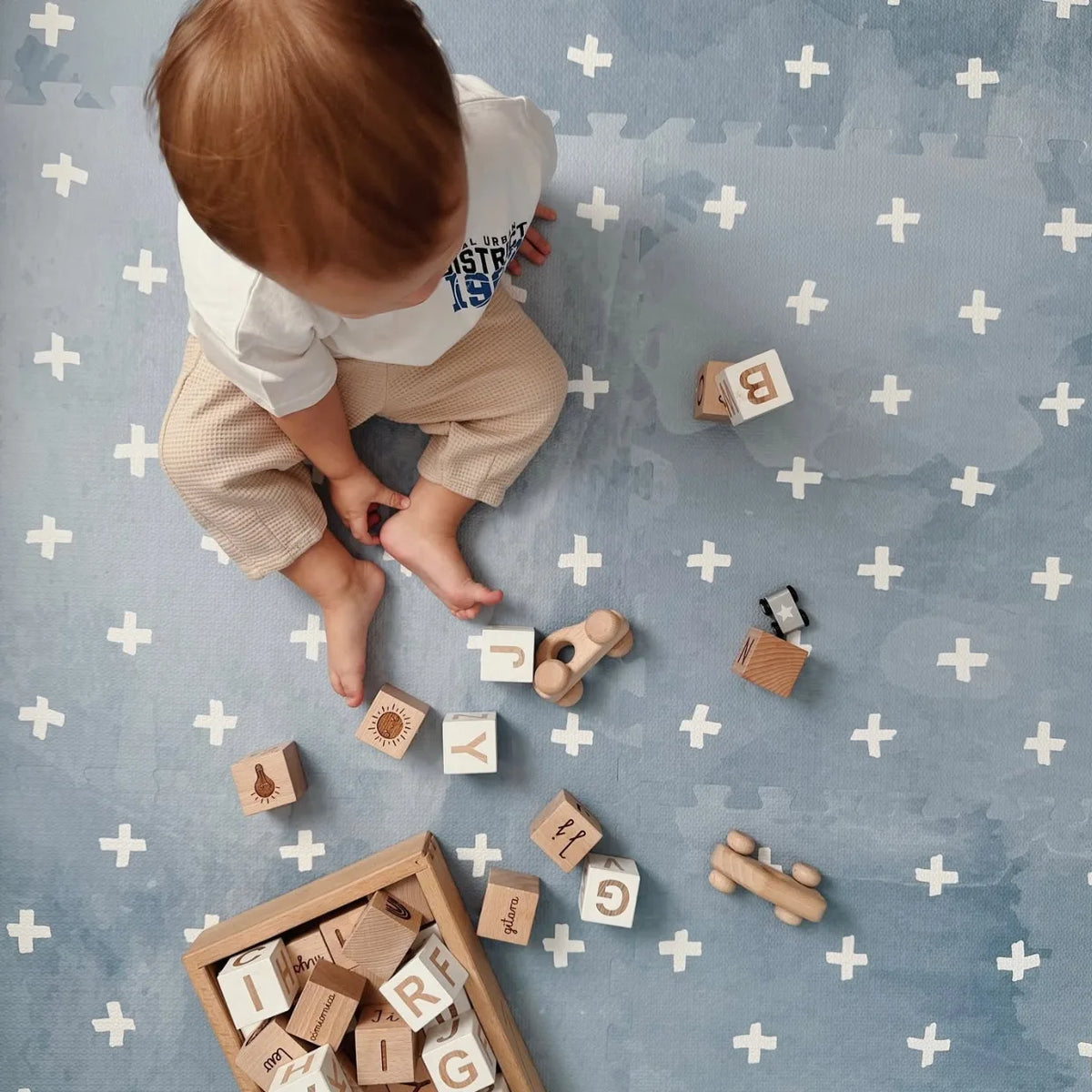 Tapis puzzle mousse motif croix — bébé de 1 an jouant avec des cubes en bois Montessori | Tinitto